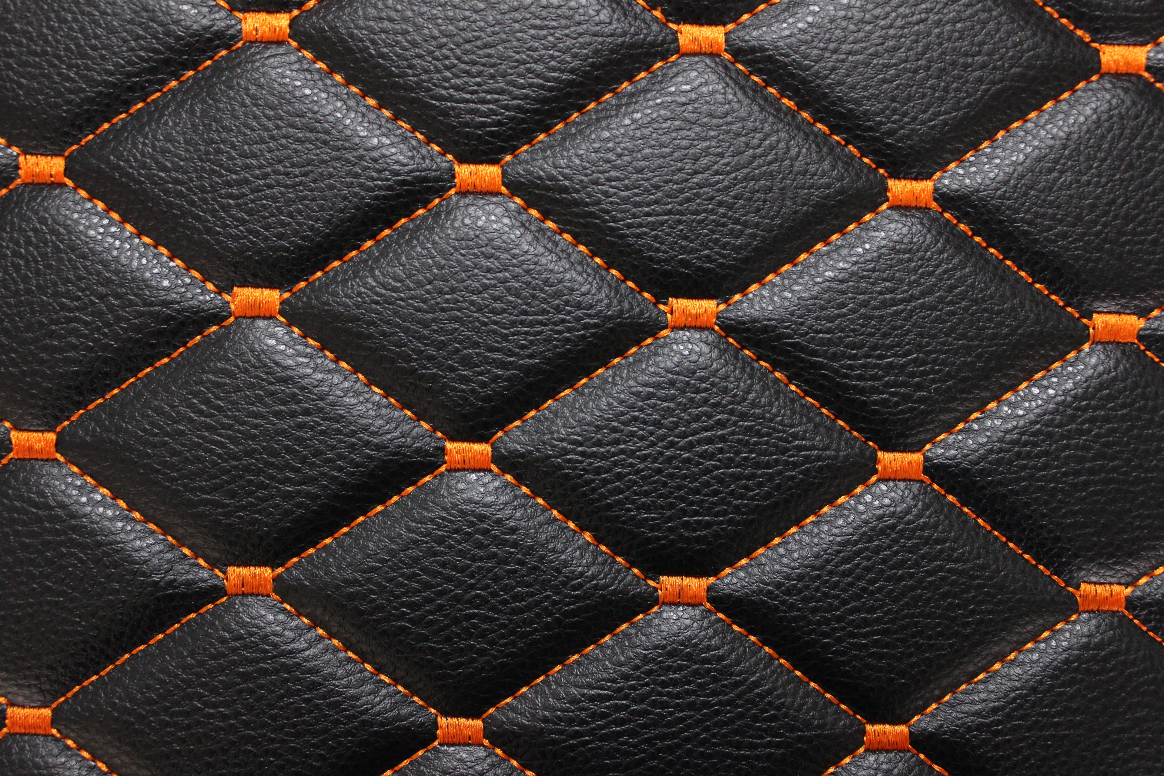 Tecido para estofos automóveis em vinil preto acolchoado laranja com textura granulada | Costura em losango de 5x8cm com espuma | 140cm e 55,1" de largura | Pele sintética (réplica)