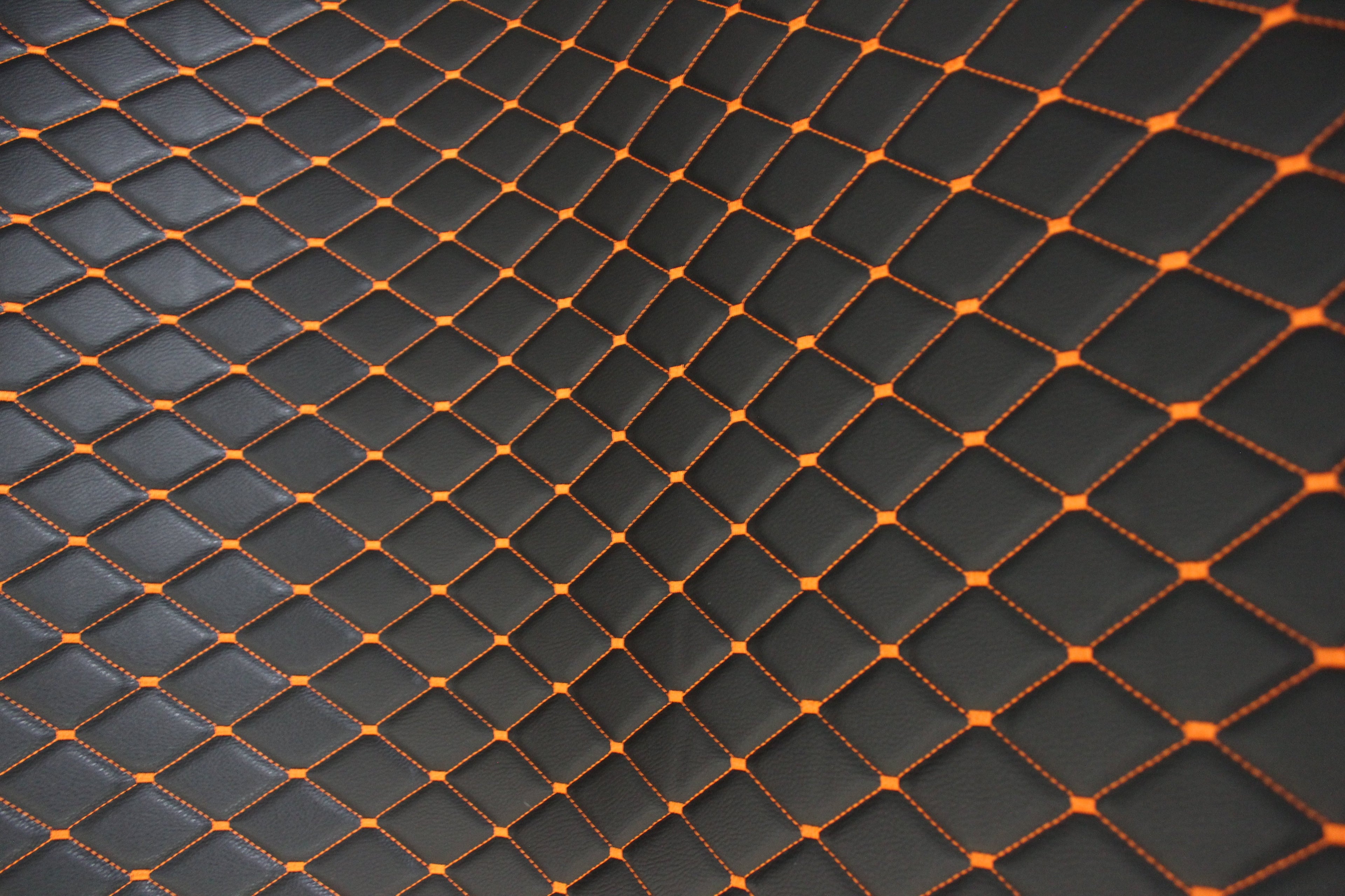 Tecido para estofos automóveis em vinil preto acolchoado laranja com textura granulada | Costura em losango de 5x8cm com espuma | 140cm e 55,1" de largura | Pele sintética (réplica)