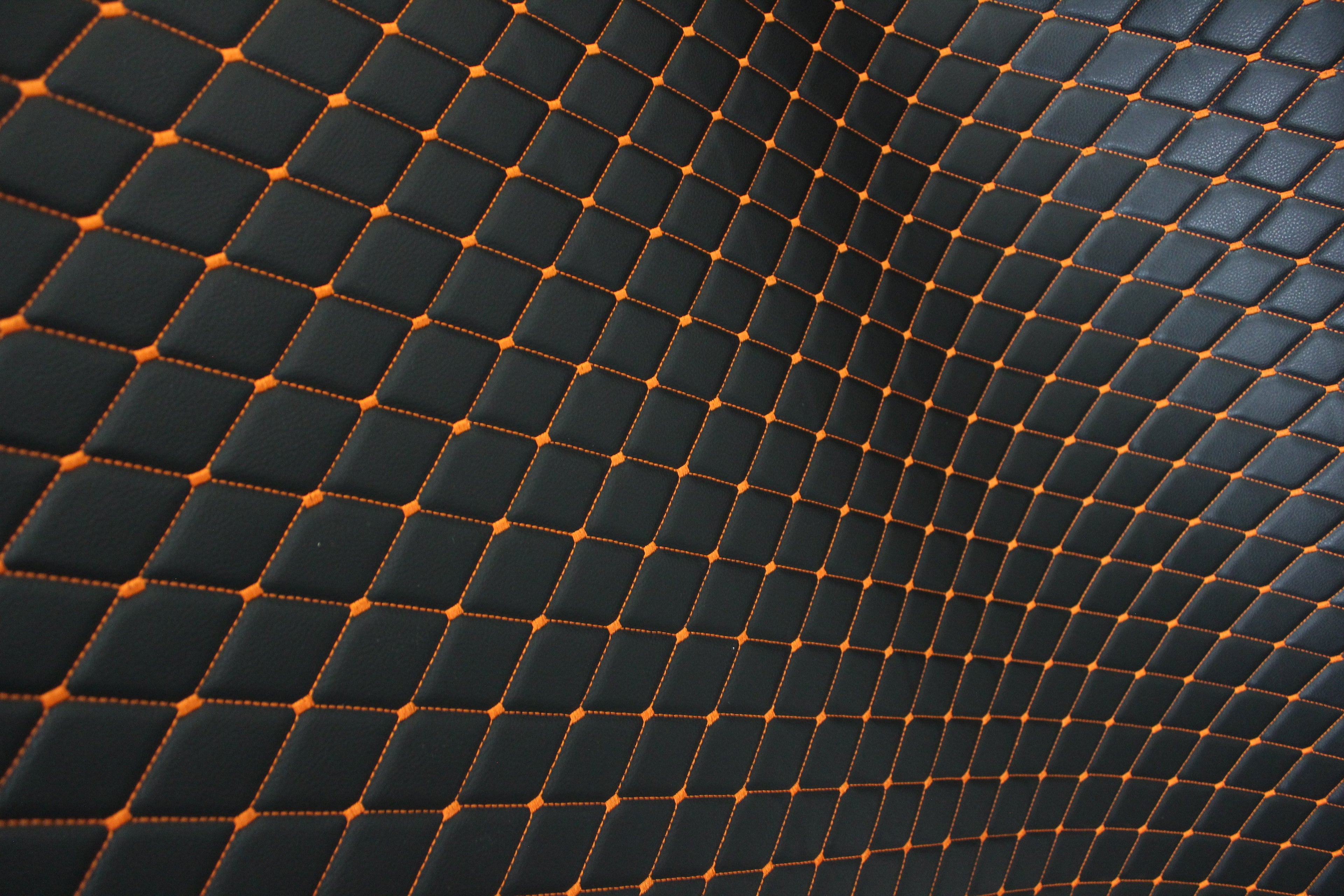 Tecido para estofos automóveis em vinil preto acolchoado laranja com textura granulada | Costura em losango de 5x8cm com espuma | 140cm e 55,1" de largura | Pele sintética (réplica)