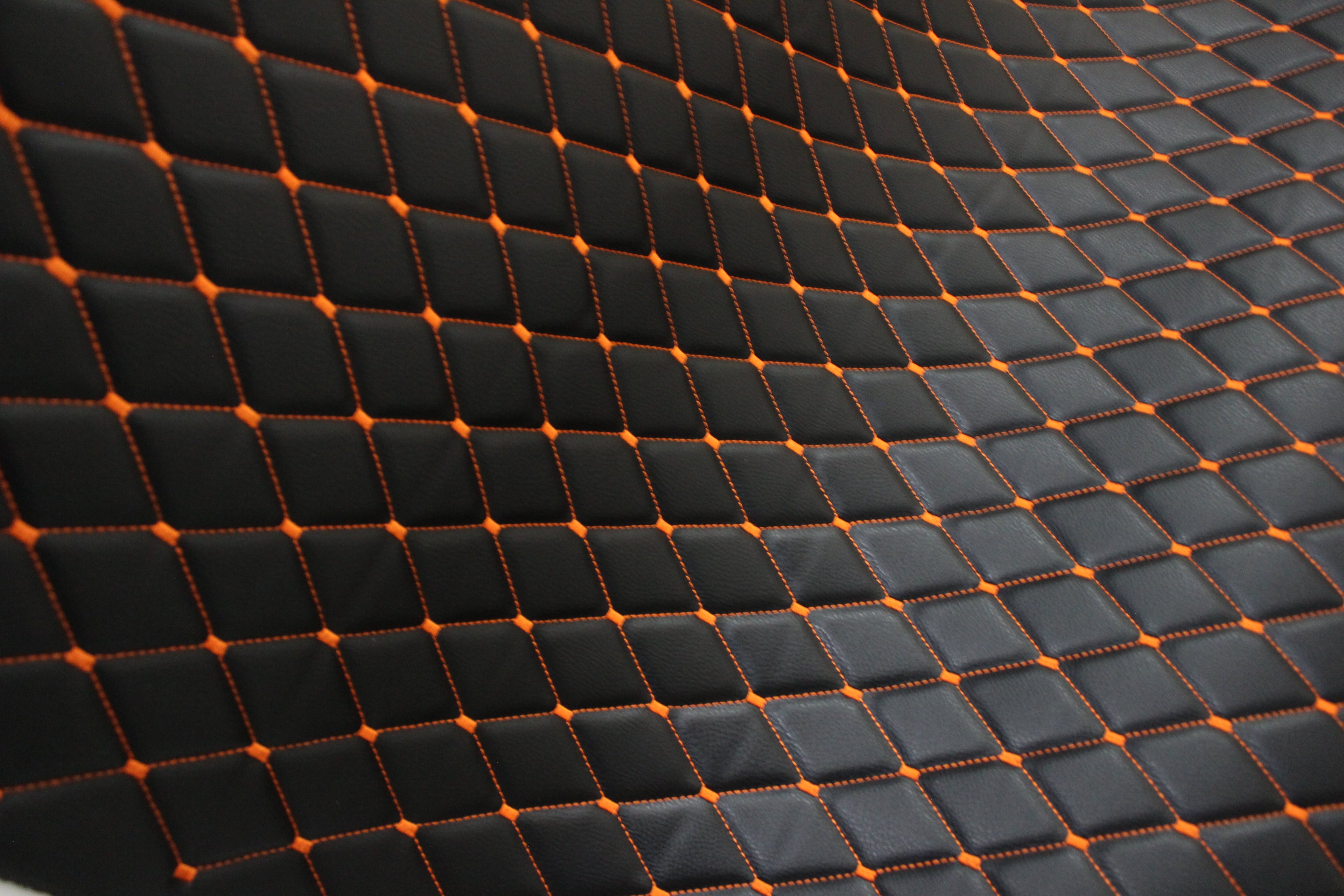 Tecido para estofos automóveis em vinil preto acolchoado laranja com textura granulada | Costura em losango de 5x8cm com espuma | 140cm e 55,1" de largura | Pele sintética (réplica)