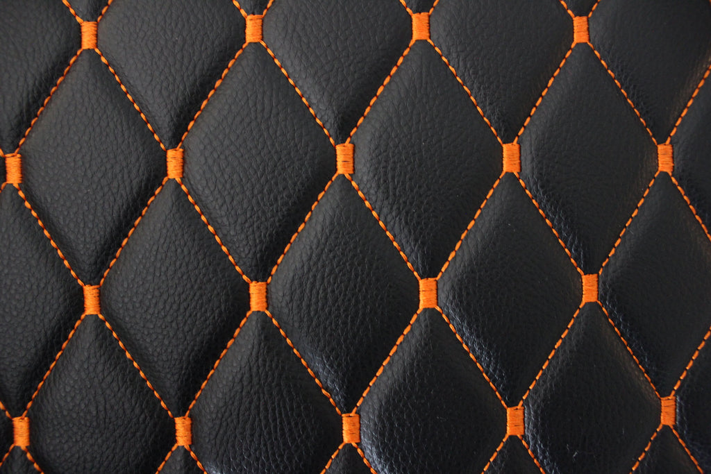 Tecido para estofos automóveis em vinil preto acolchoado laranja com textura granulada | Costura em losango de 5x8cm com espuma | 140cm e 55,1" de largura | Pele sintética (réplica)