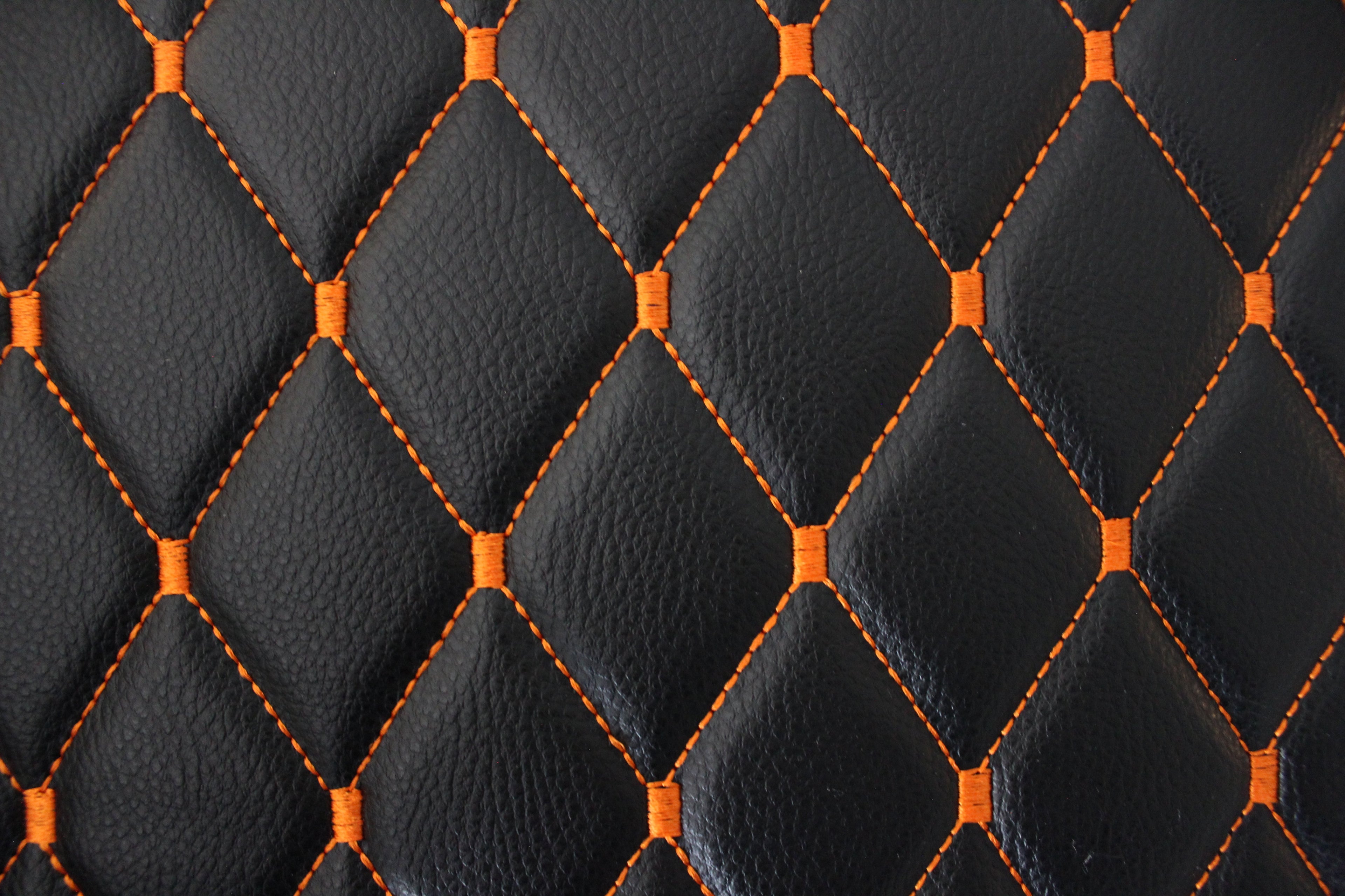 Tecido para estofos automóveis em vinil preto acolchoado laranja com textura granulada | Costura em losango de 5x8cm com espuma | 140cm e 55,1" de largura | Pele sintética (réplica)